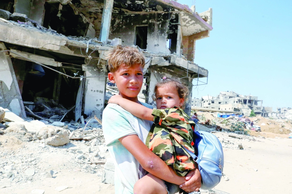 A Palestinian boy holds a girl as they flee the eastern part of Khan Yunis to make their way after they were ordered by Israeli army to evacuate their neighbourhoods in Khan Yunis on Monday. — Reuters