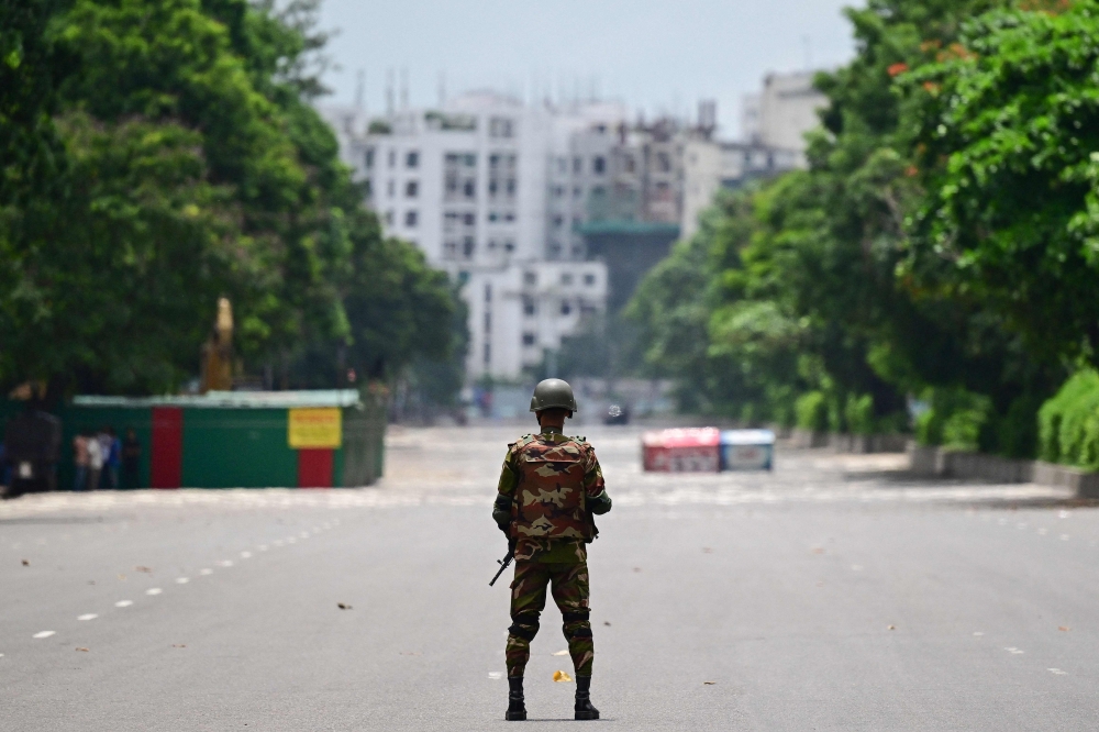 A Bangladesh army personnel stands guard near the parliament house amid a curfew following clashes between police and protestors, in Dhaka