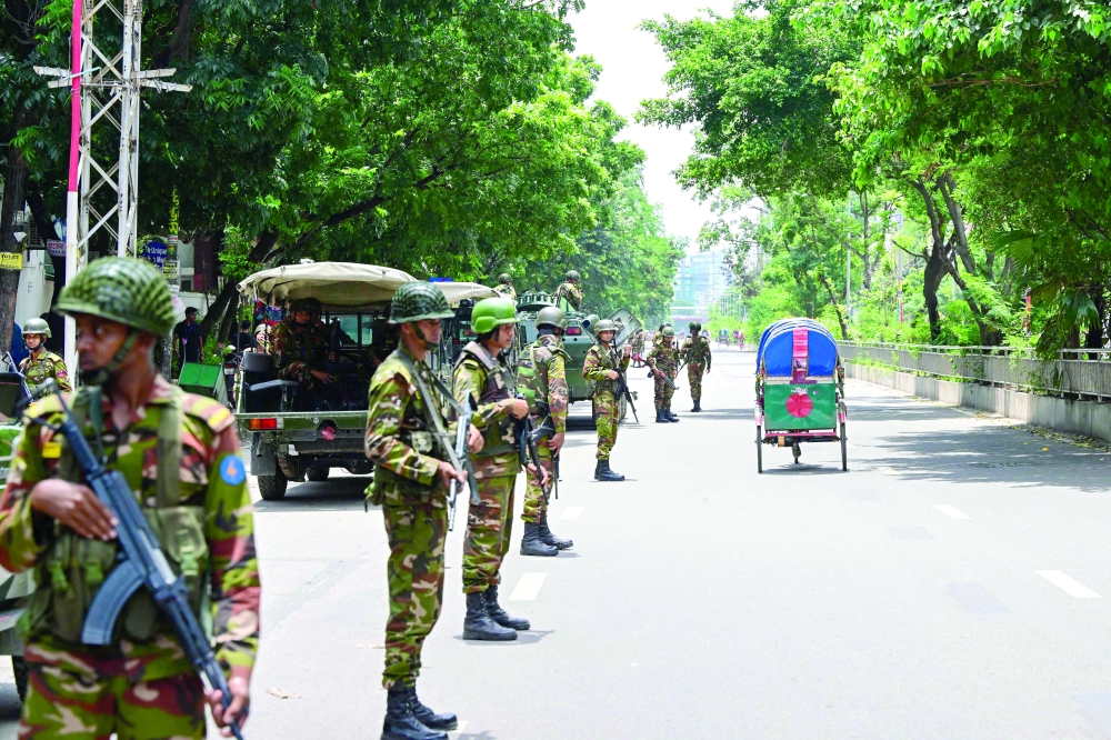 Bangladeshi soldiers stand guard along a street during a curfew amid the anti-quota protests, in Dhaka. — AFP 