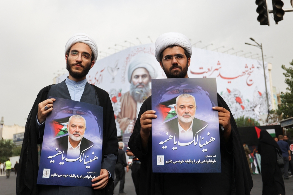 Iranians hold the poster of assassinated Hamas chief, Ismail Haniyeh during his funeral procession