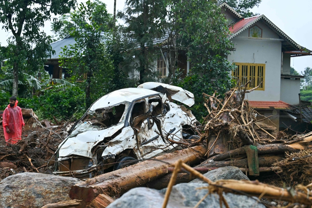 A man walks past a damaged vehicle after the landslides in Wayanad. - AFP 