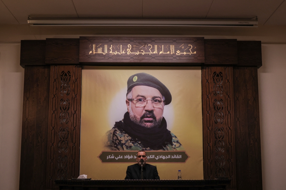 A man recites the Holy Quran as Hezbollah officials and relatives of its top commander Fuad Shukr, who was killed in an Israeli strike, attend a condolences service ahead of his funeral, in Beirut on Thursday. — Reuters