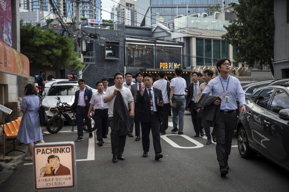Office workers walking among bars and restaurants in a busy neighborhood in Seoul, South Korea, on July 24, 2024.(Woohae Cho/The New York Times)