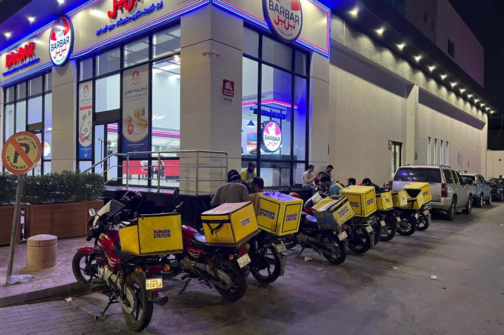 Motorcycles of delivery workers are parked outside an air-conditioned bus station in northern Riyadh