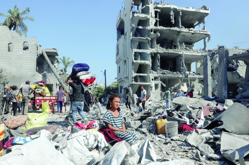 A Palestinian girl sits as people recover belongings in Deir Al Balah in the central Gaza Strip. — AFP