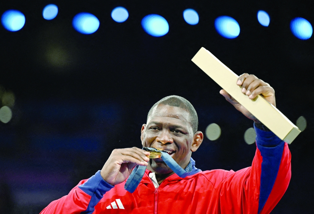 Gold medallist Mijain Lopez Nunez of Cuba bites his medal after becoming the first athlete in any sport to win the same event in five consecutive Olympics. — REUTERS