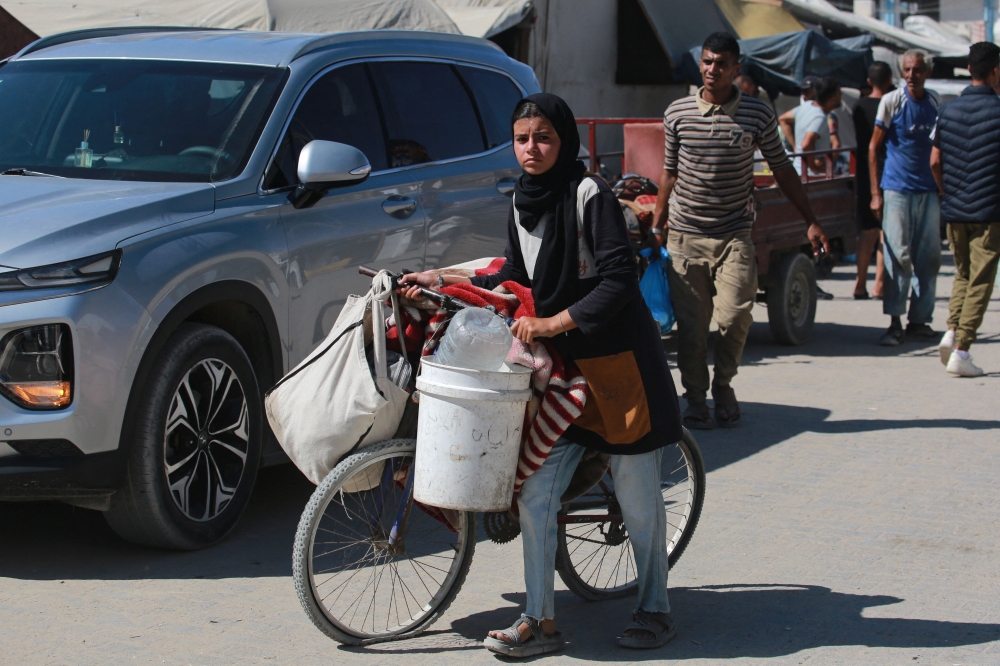 A girl pushes a loaded bicycle as displaced Palestinians leave an area in east Khan Yunis towards the west in the southern Gaza Strip amid the ongoing conflict between Israel and Hamas. - AFP