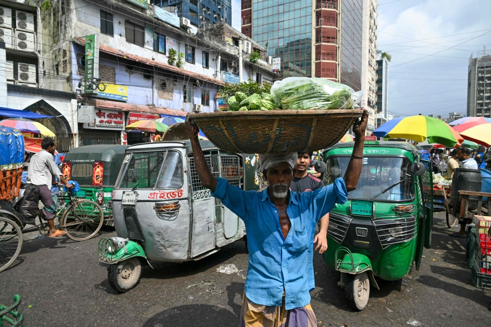 A man carries a basket of vegetables at a market in Dhaka 