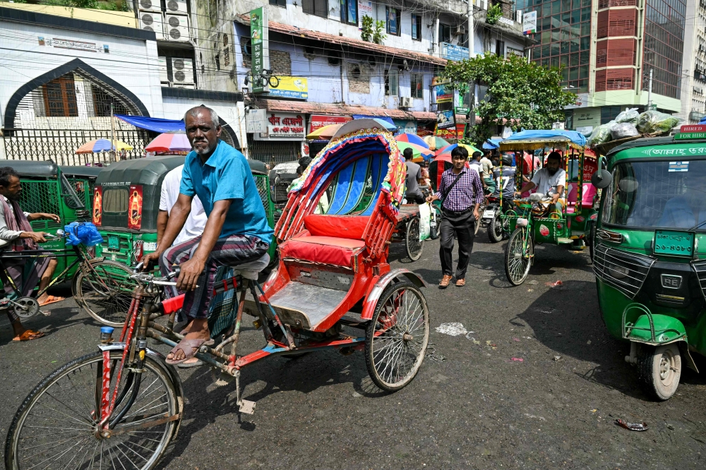 A rickshaw puller waits for customers at a market in Dhaka on August 10, 2024