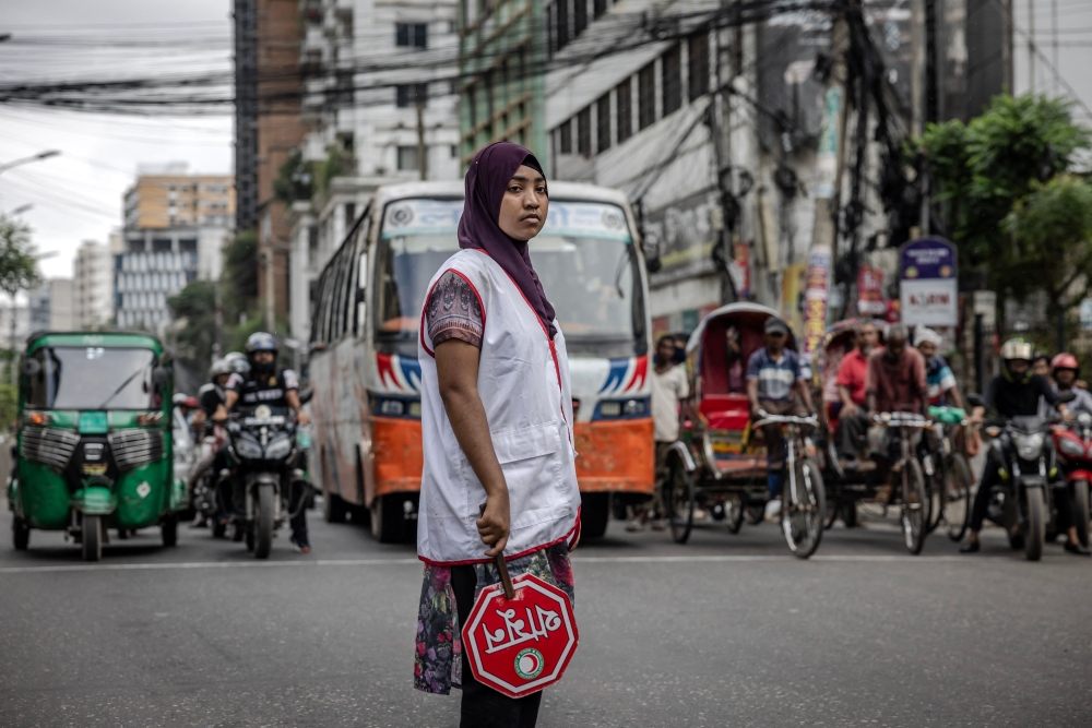 Commuters wait at a road crossing while Bangladeshi students control the traffic as police went on strike in Dhaka 