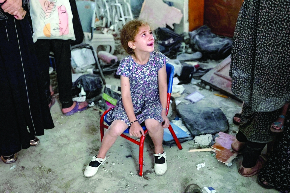 A young girl cries inside a school used as a temporary shelter for displaced Palestinians in Gaza City, following an Israeli strike on Saturday. - AFP