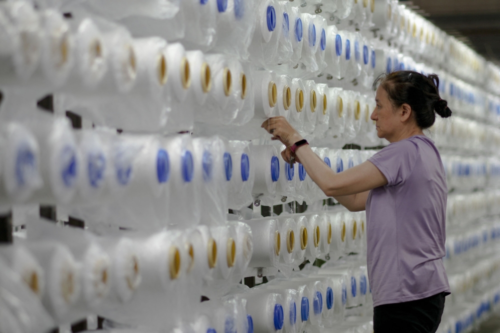 This picture taken on July 5, 2024 shows an employee working at the Creative Tech Textile company which repurposes discarded oyster shells into Seawool, a trademarked and patented fabric, at its factory in Tainan. Growing up on Taiwan's west coast where mollusc farming is popular, Eddie Wang saw discarded oyster shells transformed from waste to function -- a memory that inspired him to create a unique and environmentally friendly fabric called "Seawool".  
 - To go with: TAIWAN-ENVIRONMENT-AGRICULTURE-BUSINESS-RECYCLE-TEXTILE, FEATURE by Amber WANG
 (Photo by Sam Yeh / AFP) / To go with: TAIWAN-ENVIRONMENT-AGRICULTURE-BUSINESS-RECYCLE-TEXTILE, FEATURE by Amber WANG

