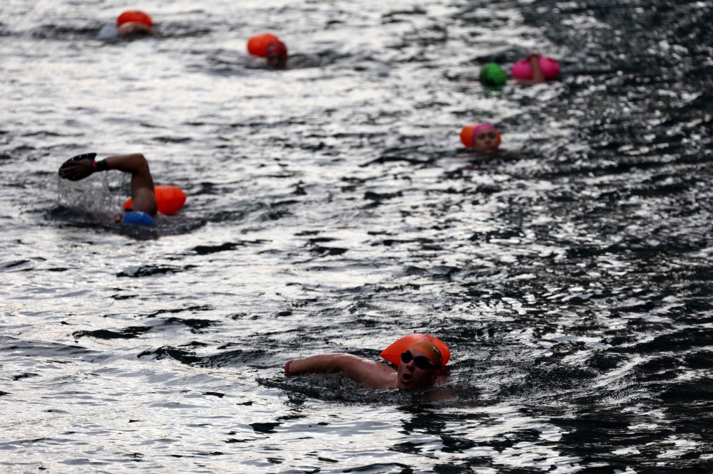 eople swim in the Middle Dock of Canary Wharf in east London, on August 12, 2024, on what is set to be the hottest day of the year in the UK so far. (Photo by Adrian DENNIS / AFP)

