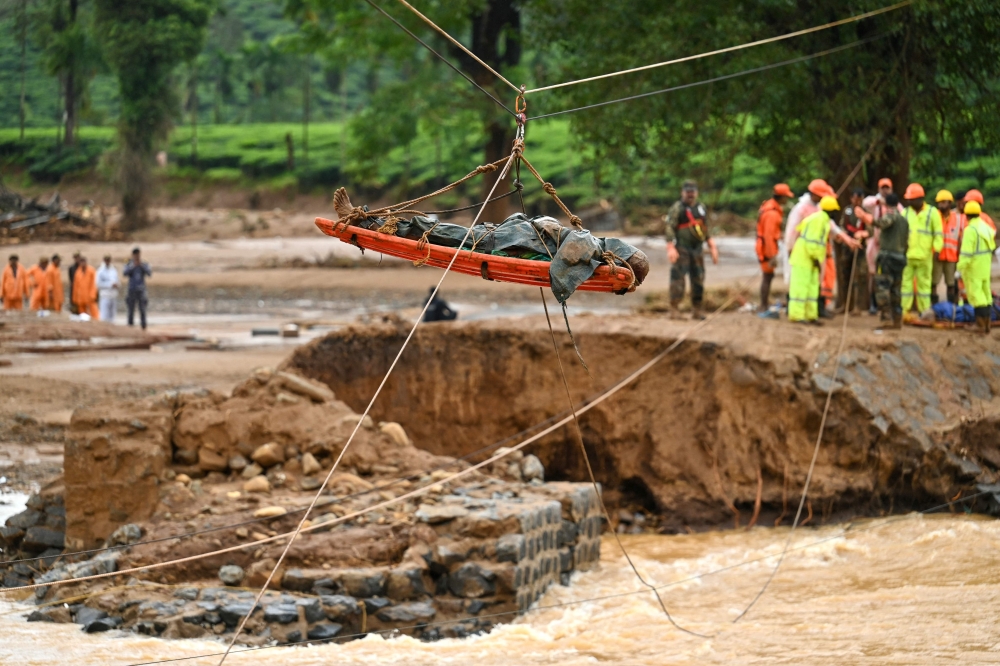 Relief personnel lift the body of a deceased, during a search and rescue operation after landslides in Wayanad on July 31