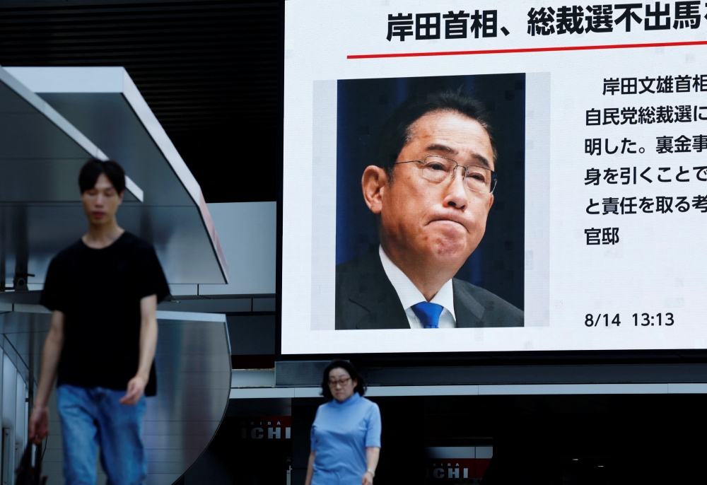 People walk past a large screen showing the news about Japanese Prime Minister Fumio Kishida's announced resignation next month in Tokyo. - Reuters

