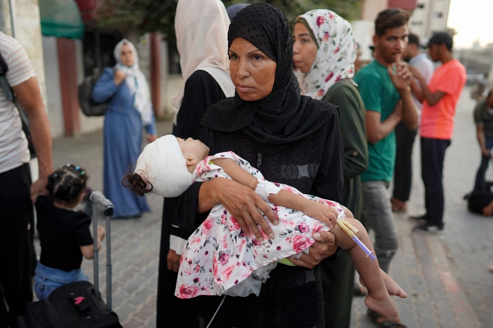 A woman carries a child at Al-Nasser hospital in Khan Yunis on August 15, 2024