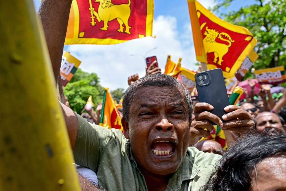 Supporters of Sri Lanka's President and UNP presidential candidate Ranil Wickremesinghe cheer as he leaves the Election Commission office after filing his nomination papers for the upcoming presidential elections in Colombo. - AFP