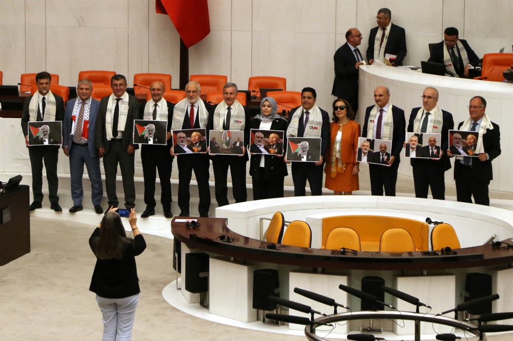 Turkey's ruling AK Party lawmakers hold pictures of late Hamas leader Ismail Haniyeh and late Turkish Prime Minister Necmettin Erbakan at the General Assembly after Palestinian President Mahmoud Abbas' address at the Turkish parliament in Ankara, Turkey August 15, 2024. REUTERS/Cagla Gurdogan
