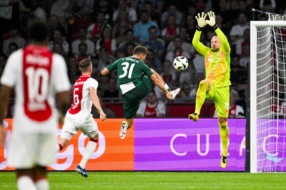Ajax's Dutch goalkeeper #22 Remko Pasveer (R) attempts to block the ball from Panathinaikos' Serbian midfielder #31 Filip Duricic (C) during the UEFA Europa League 3rd Qualifying Round 

 - Netherlands OUT
 (Photo by Olaf Kraak / ANP / AFP)