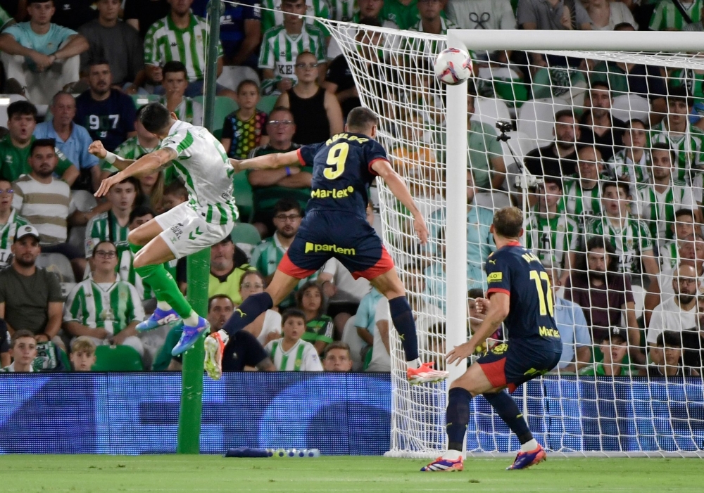 Marc Bartra (L) scores his team's first goal during the Spanish league football match between Real Betis and Girona FC 