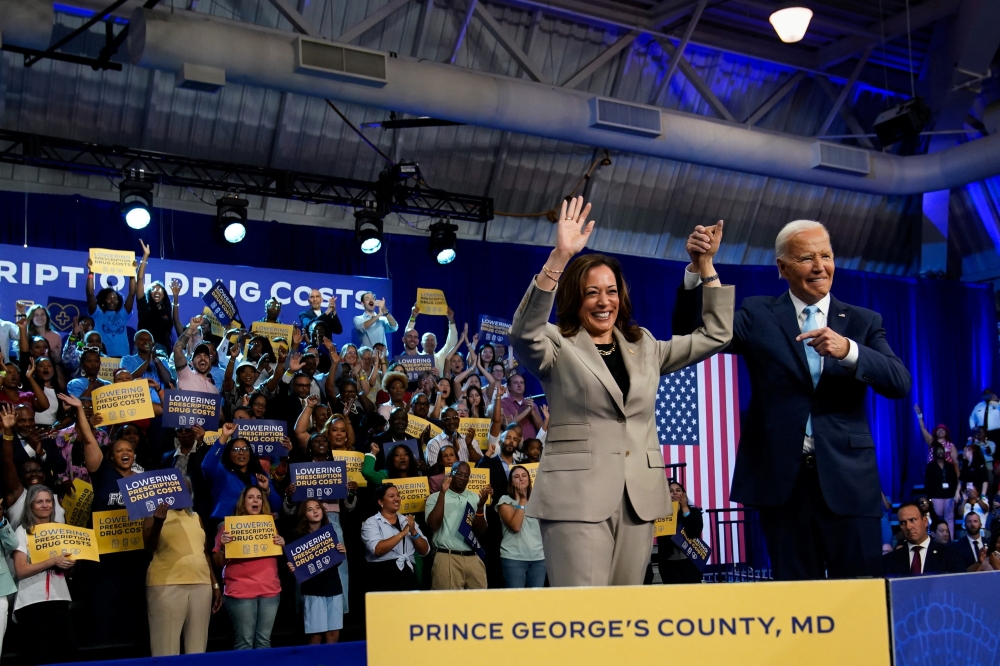 US President Joe Biden raises the hand of Vice President Kamala Harris, at an event on Medicare drug price negotiations, in Prince George's County