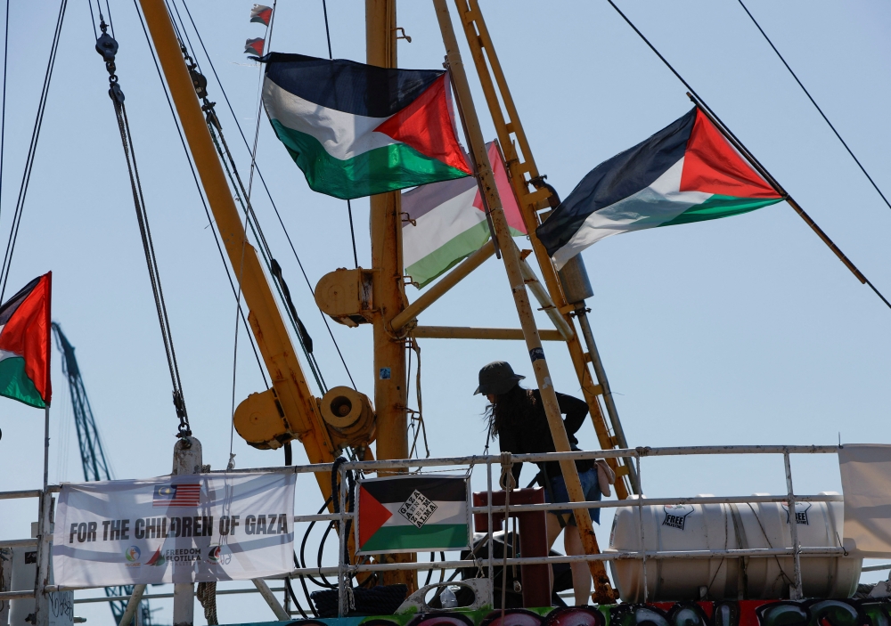 An activist washes the deck of the Freedom Flotilla Coalition ship 'Handala' as they prepare to sail for Gaza 