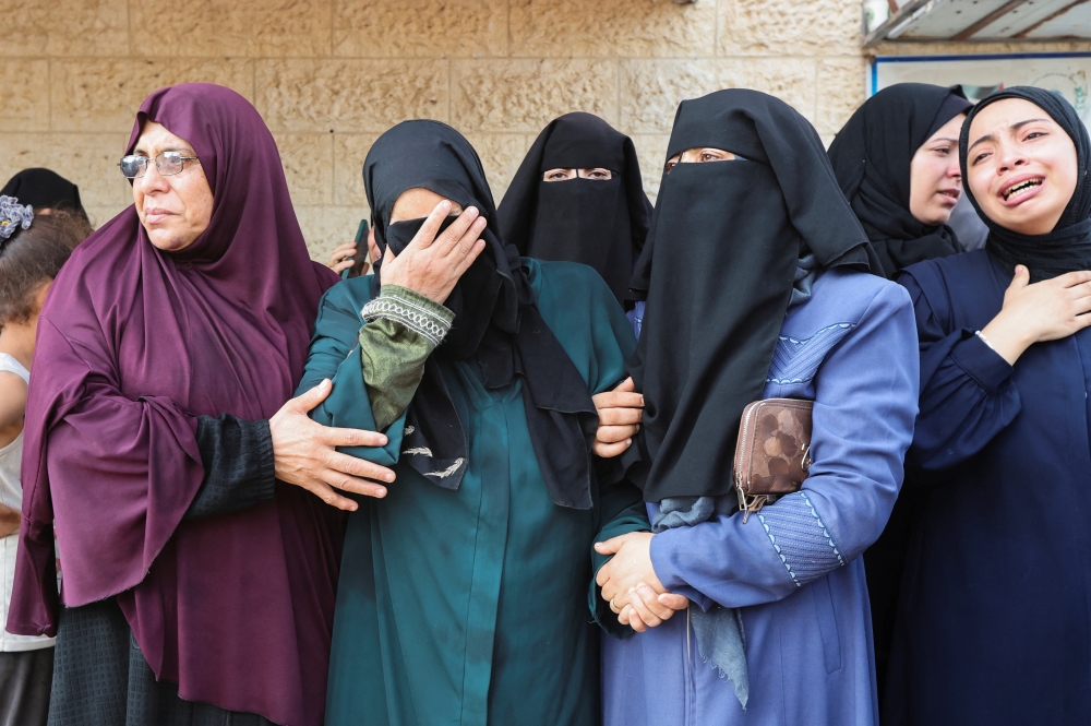 Palestinian women mourn for the Palestinians killed in Israeli strikes