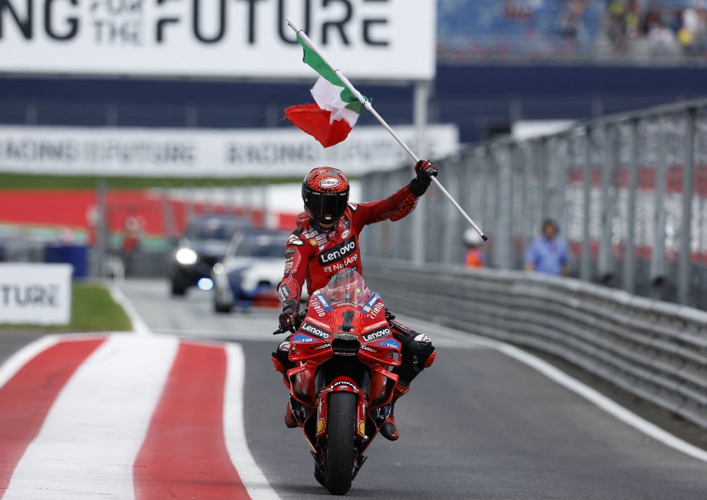 Francesco Bagnaia celebrates with his national flag after winning the Austrian MotoGP race at the Red Bull Ring 
