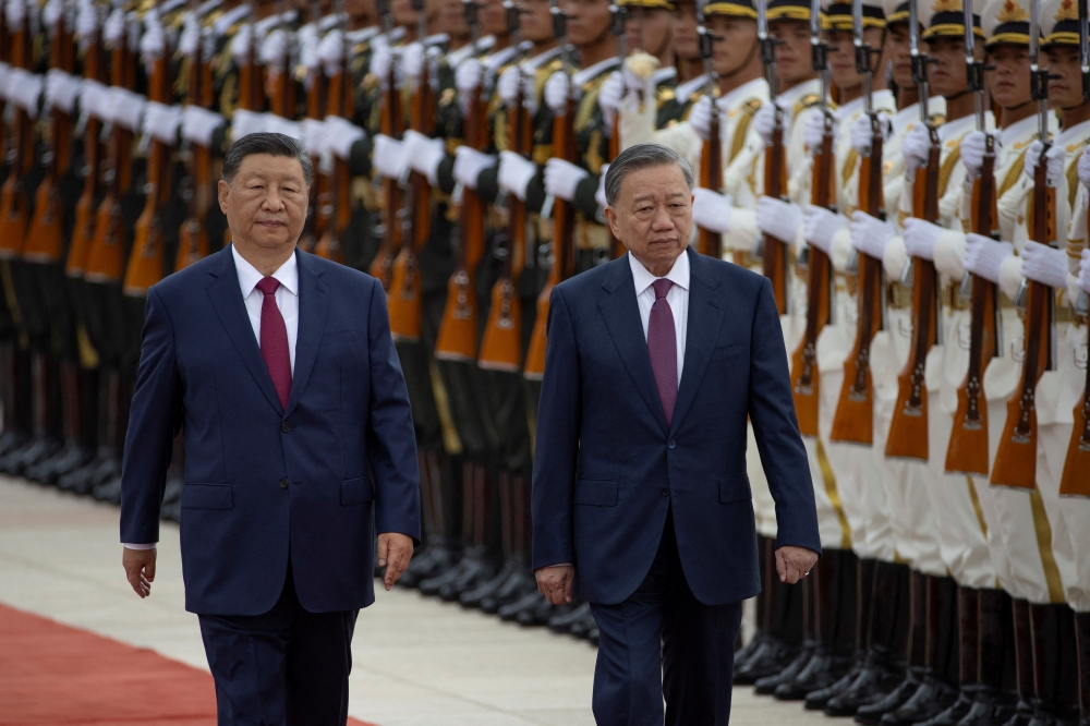 Chinese President Xi Jinping walks next to Vietnam's President To Lam as they pass by the honour guard  
