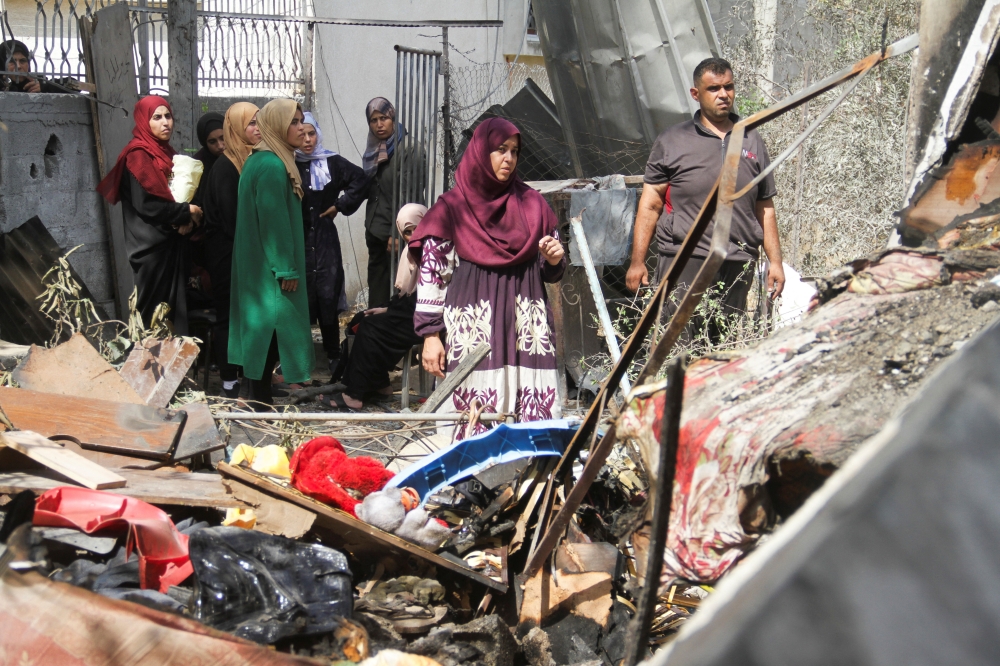 Palestinians stand at the site of an Israeli strike on a house, amid the Israel-Hamas conflict, in Beit Lahia in the northern Gaza Strip. - Reuters