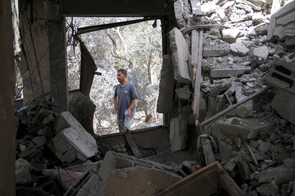 A Palestinian man stands at the site of an Israeli strike on a house, amid the Israel-Hamas conflict, in Beit Lahia in the northern Gaza Strip - Reuters