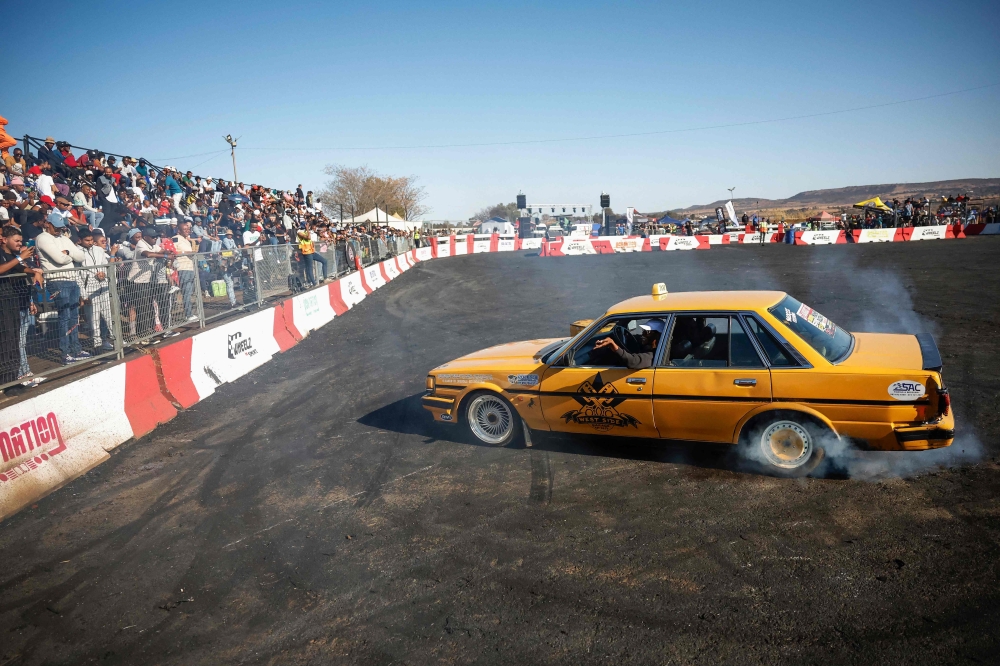 A man interacts with spectators while they drift their car during a round of spinning at Wheelz n Smoke Arena in the south of Johannesburg 