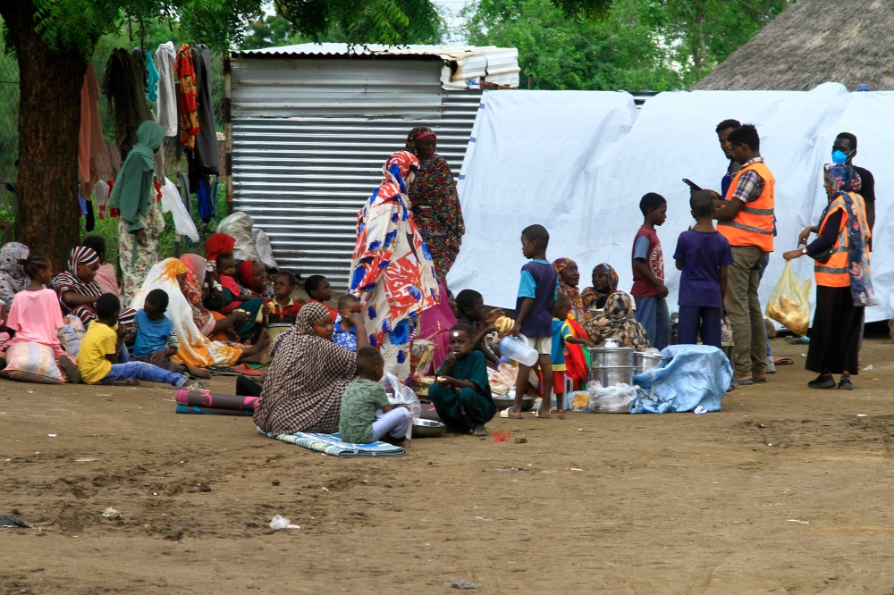 Sudanese, displaced from the town of Sinjah, receive humanitarian aid at their makeshift camp 