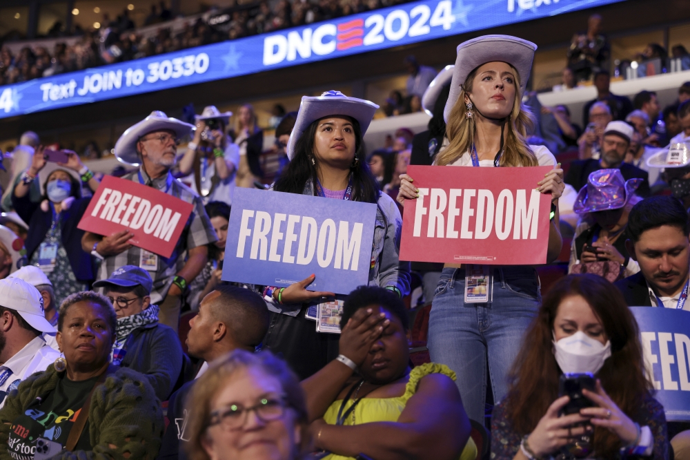 Attendees hold signs reading “Freedom” as they listen to a speaker on the second day of the Democratic National Convention, in Chicago