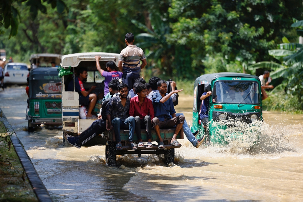 People move on vehicles on a flooded Dhaka-Chattogram highway in the Chhagalnaiya area, in Feni, Bangladesh. — Reuters 