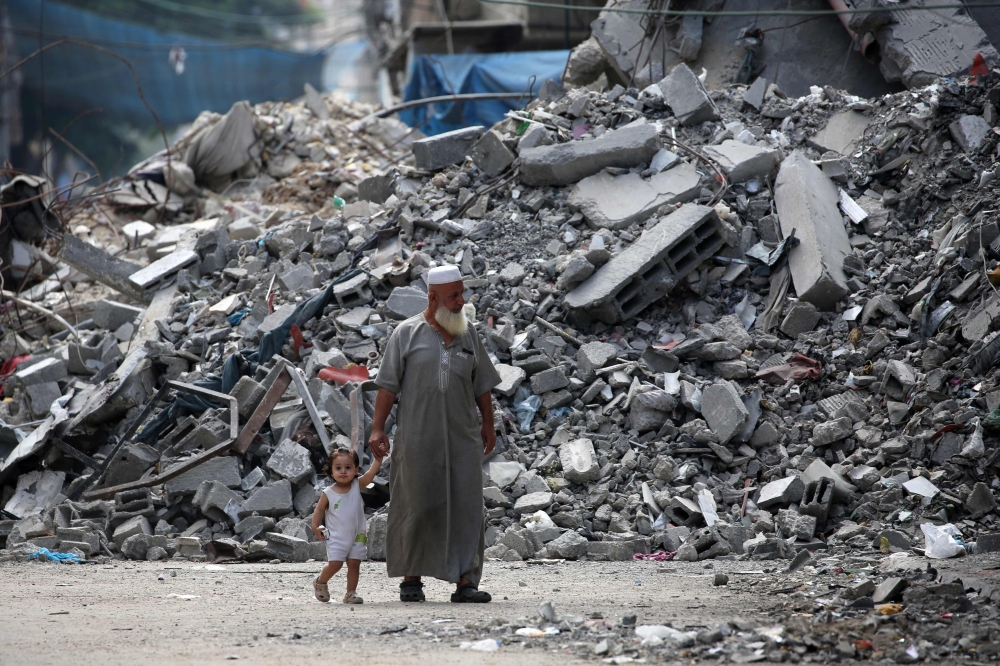 An elderly man and a child walk past a building levelled by Israeli bombardment in the Bureij refugee camp, in Gaza. — AFP 