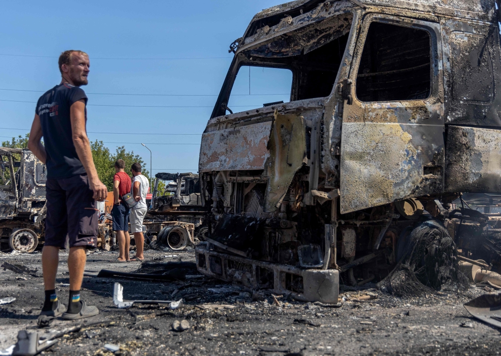 People look at burnt-out trucks on a site following an air attack, in the Odesa region, Ukraine. — AFP