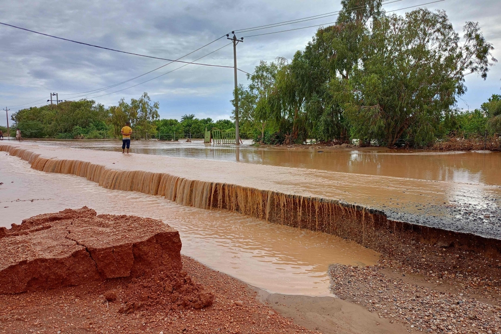 A Sudanese man walks on a flooded street in the town of Tangasi, in Sudan's Meroe province. — AFP 