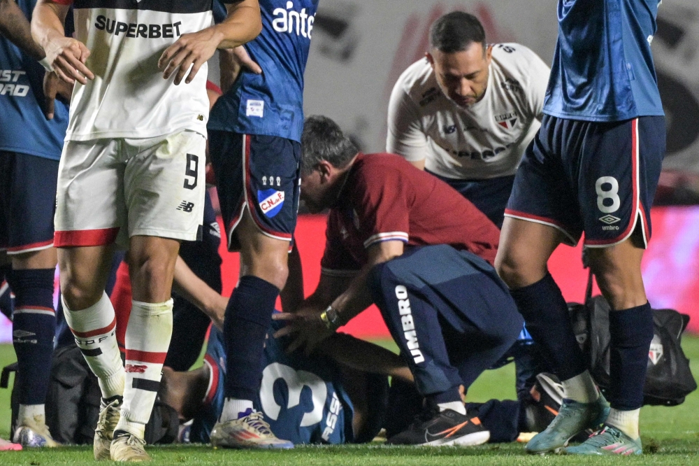 Nacional's defender Juan Manuel Izquierdo receives medical attention after collapsing onto the ground
