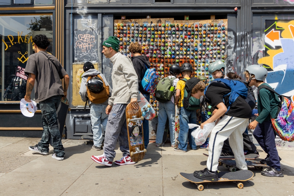 Shawn Connolly, wearing a green hat, heads down Divisadero Street with his San Francisco Skate Club summer camp on June 18, 2024. (Jason Henry/The New York Times)