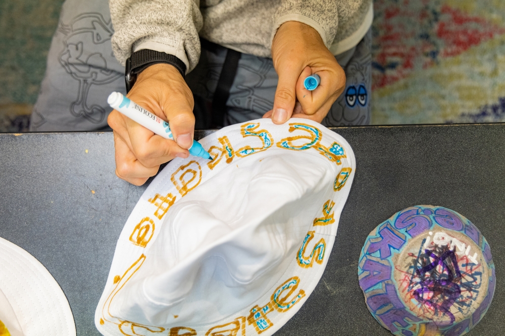 Shawn Connolly participates in a bucket hat drawing activity with children at the San Francisco Skate Club on June 18, 2024. (Jason Henry/The New York Times)