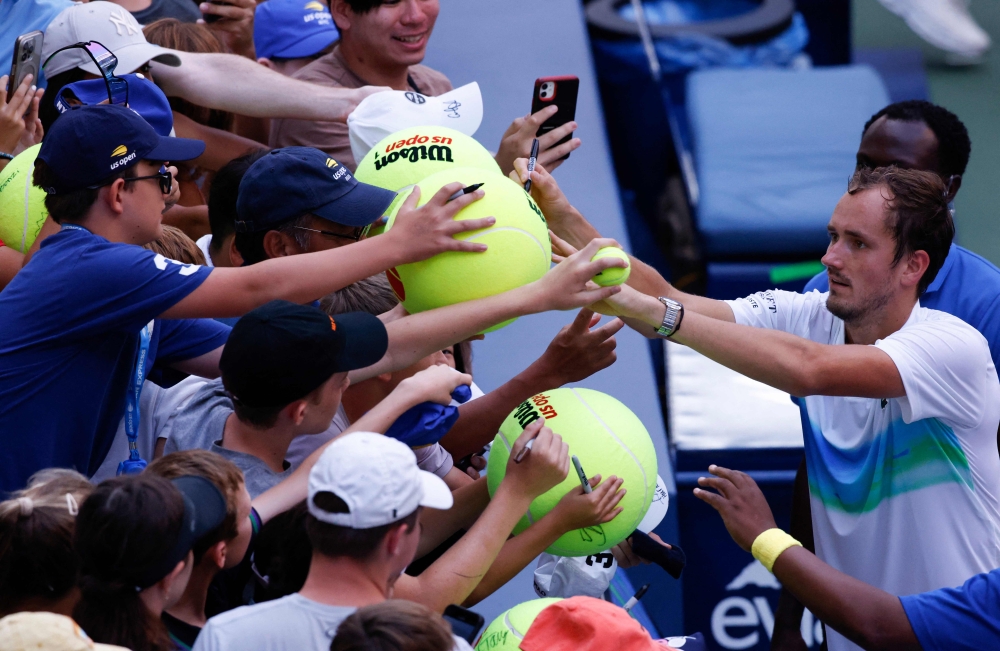 Russia's Daniil Medvedev signs giant tennis balls for fans after defeating Serbia's Dusan Lajovic in their men's singles first round match on day two of the US Open tennis tournament at the USTA Billie Jean King National Tennis Center in New York City, on August 27, 2024. (Photo by Kena Betancur / AFP)

