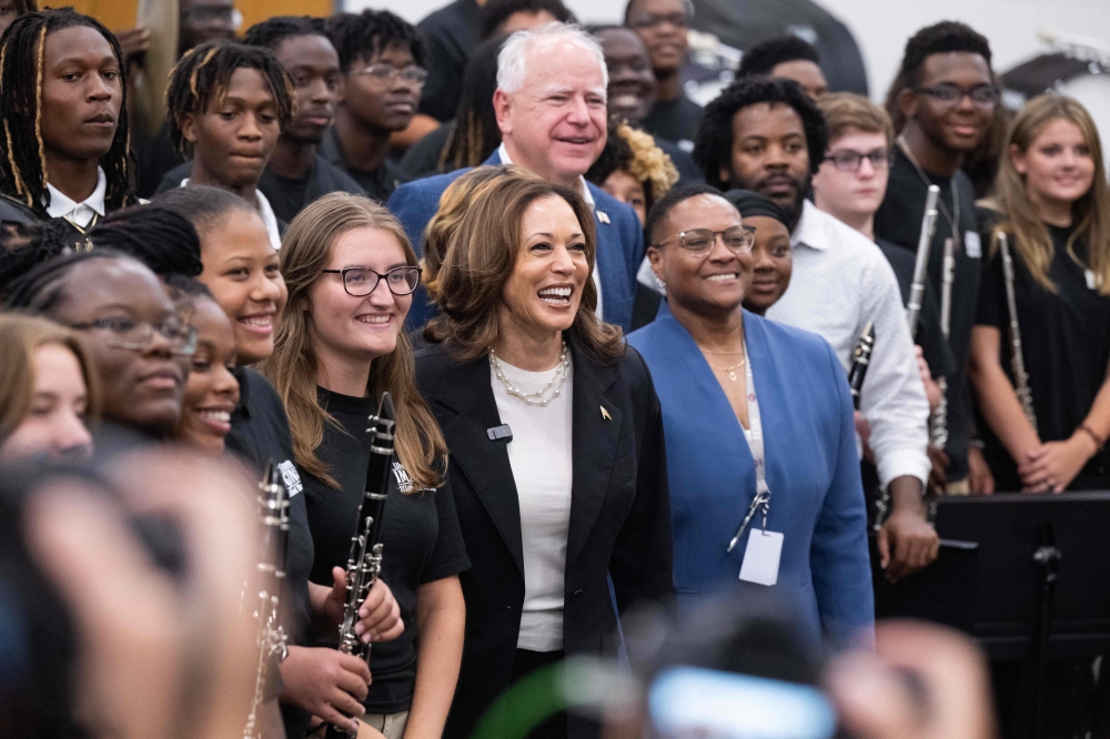 TOPSHOT - Democratic presidential candidate US Vice President Kamala Harris and her running mate, Governor Tim Walz, pose with members of the marching band during a visit at Liberty County High School in Hinesville, Georgia,  August 28, 2024, as they travel across Georgia for a 2-day campaign bus tour. (Photo by SAUL LOEB / AFP)

