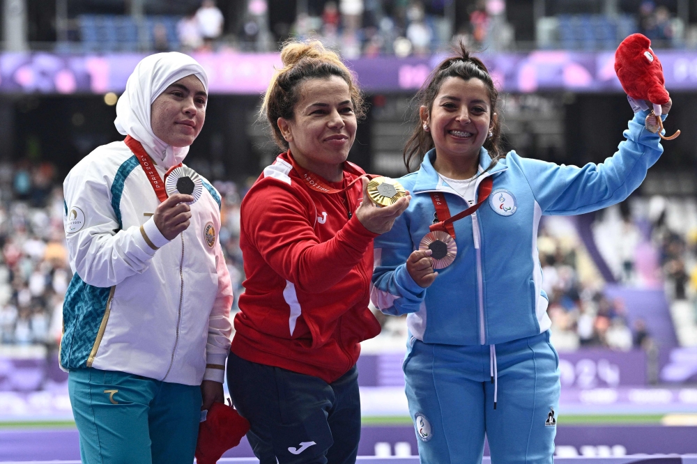 Silver medalist Uzbekistan's Kubaro Khakimova (L), gold medalist Tunisia's Raoua Tlili and bronze medalist Argentine's Antonella Ruiz Diaz celebrate on the podium during the victory ceremony 