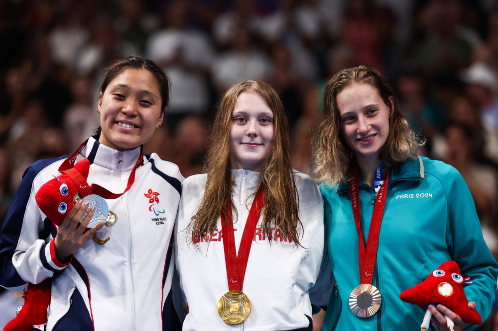 (L/R) Silver medalist Hong Kong's Yui Lam Chan, gold medalist Britain's Poppy Maskill and bronze medalist Neutral Paralympic Athletes' Valeriia Shabalina celebrate on the podium of the women's S14 100m butterfly swimming event  