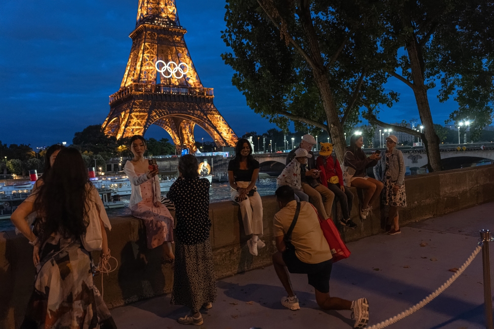 Tourists gather on the banks of the Seine River near the Eiffel Tower in Paris, July 23, 2024. (Daniel Berehulak/The New York Times)