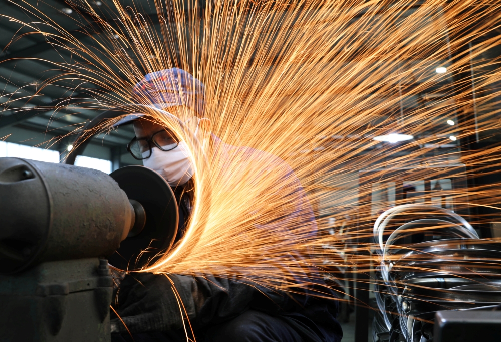 A worker wearing a face mask works on a production line manufacturing bicycle steel rim at a factory in Hangzhou, Zhejiang. — Reuters
