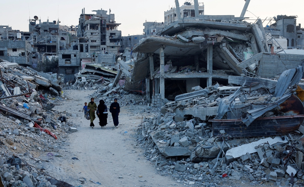 Palestinian walk amidst the rubble of buildings destroyed after an Israeli strike, in Khan Younis. — Reuters 