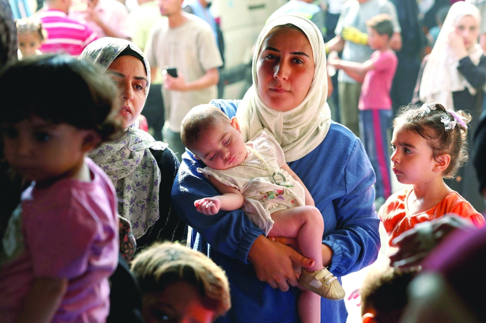 A displaced Palestinian mother carries her daughter as she waits to get her vaccinated against polio, in Deir Al Balah, in the central Gaza Strip, on Monday. - Reuters