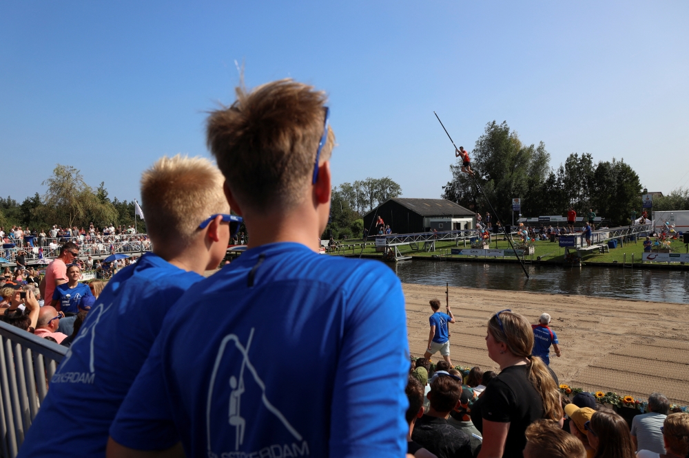People watch as a contestant takes part in a yearly national 'fierljeppen' or canal vaulting contest in the village of Polsbroekerdam, Netherlands August 31, 2024. REUTERS/Bart Biesemans
